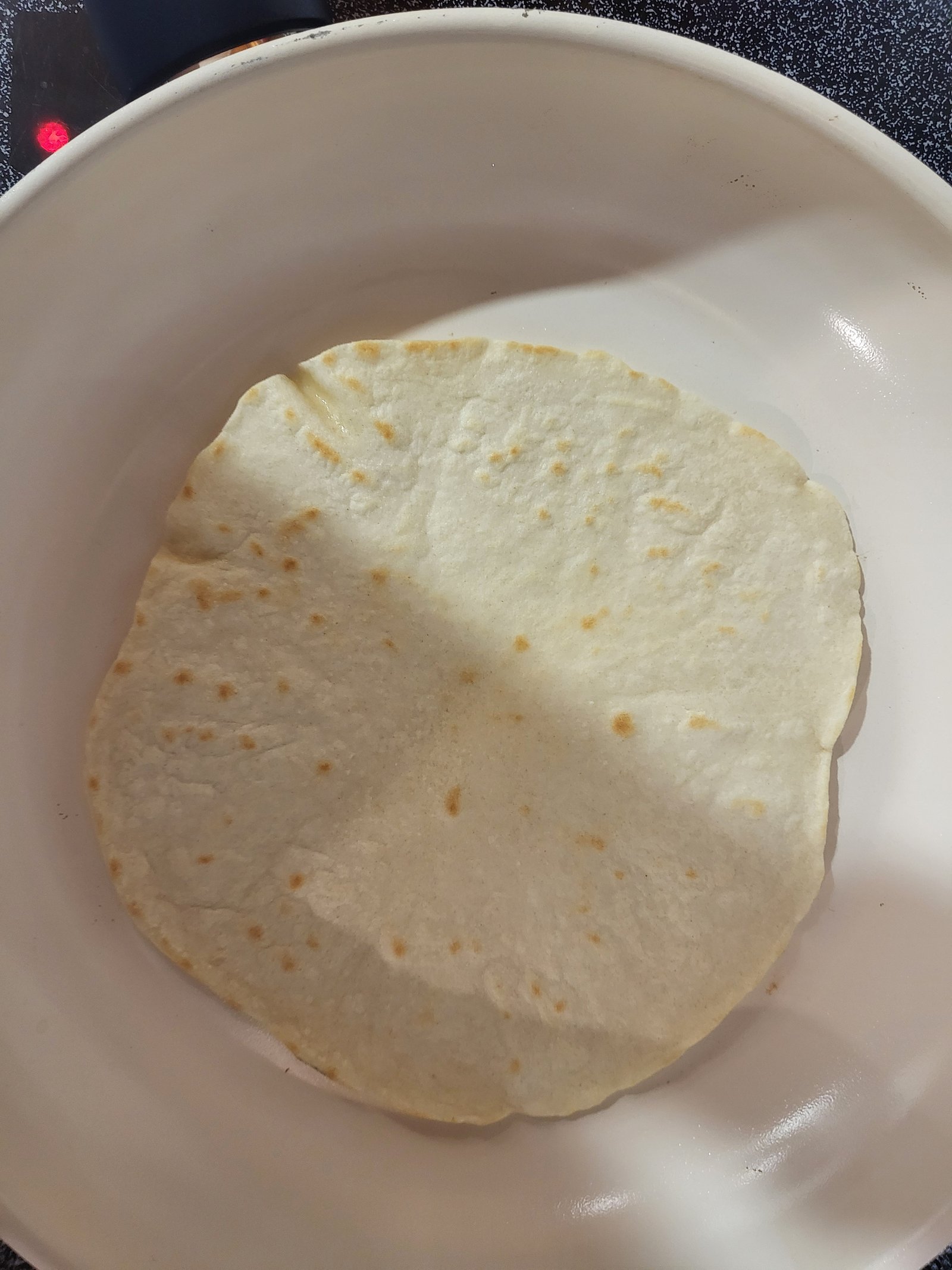 tortilla cooking in a white pan