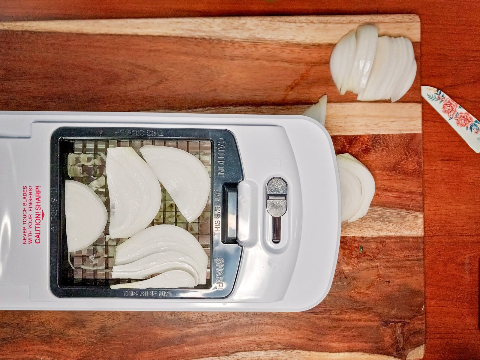 onion slices on the cutting surface of a dicer