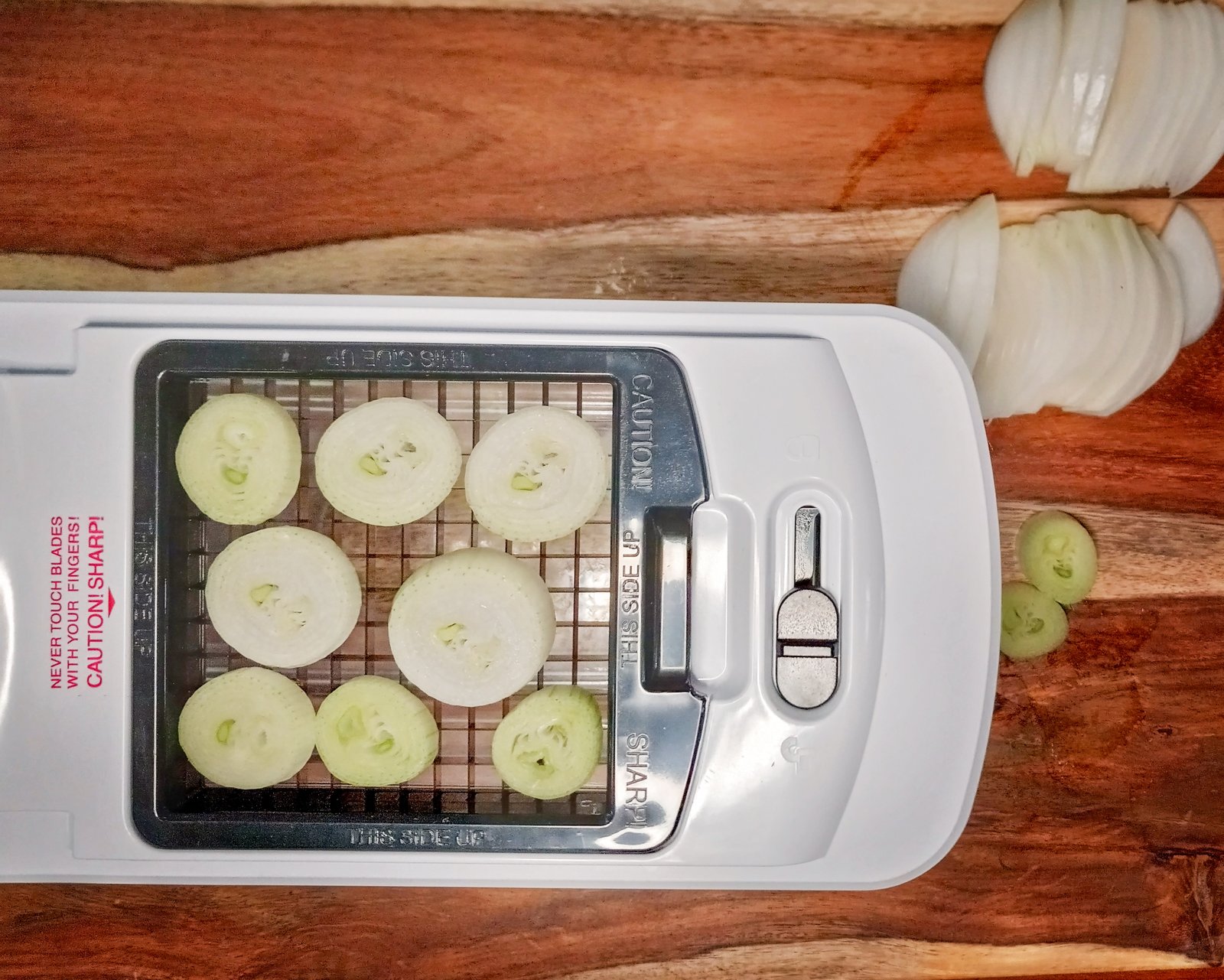 onion stem slices on the cutting board of a dicer