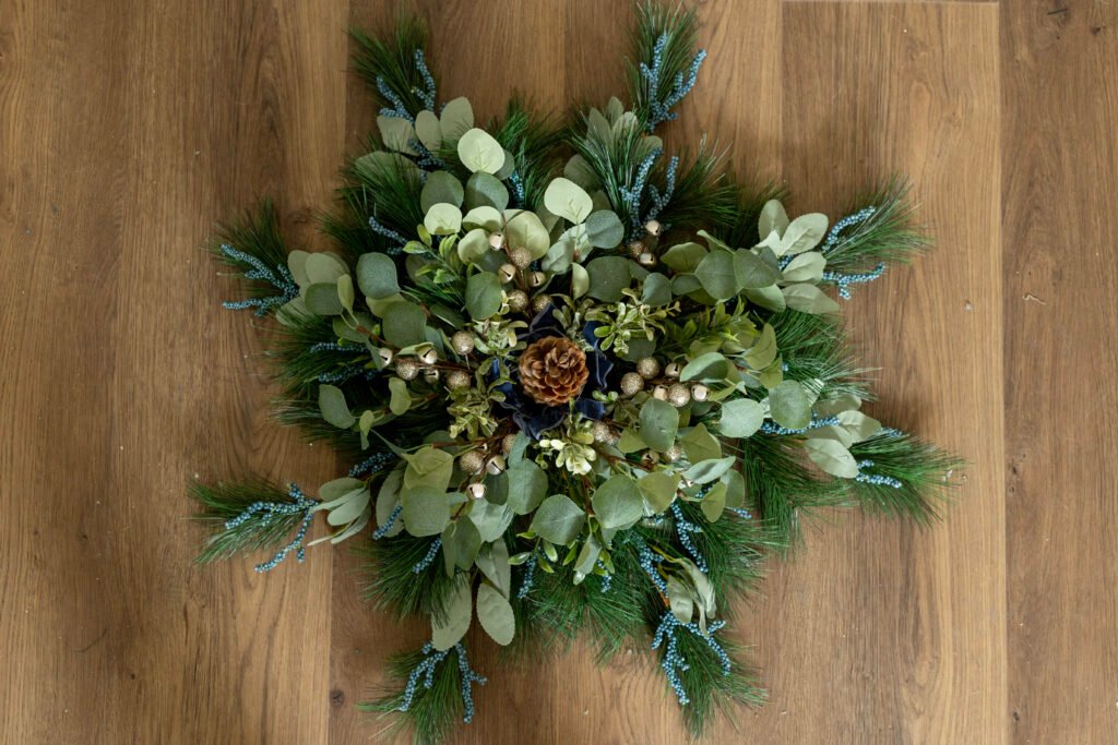 Completed Christmas wreath with blue and gold accents against a background of green