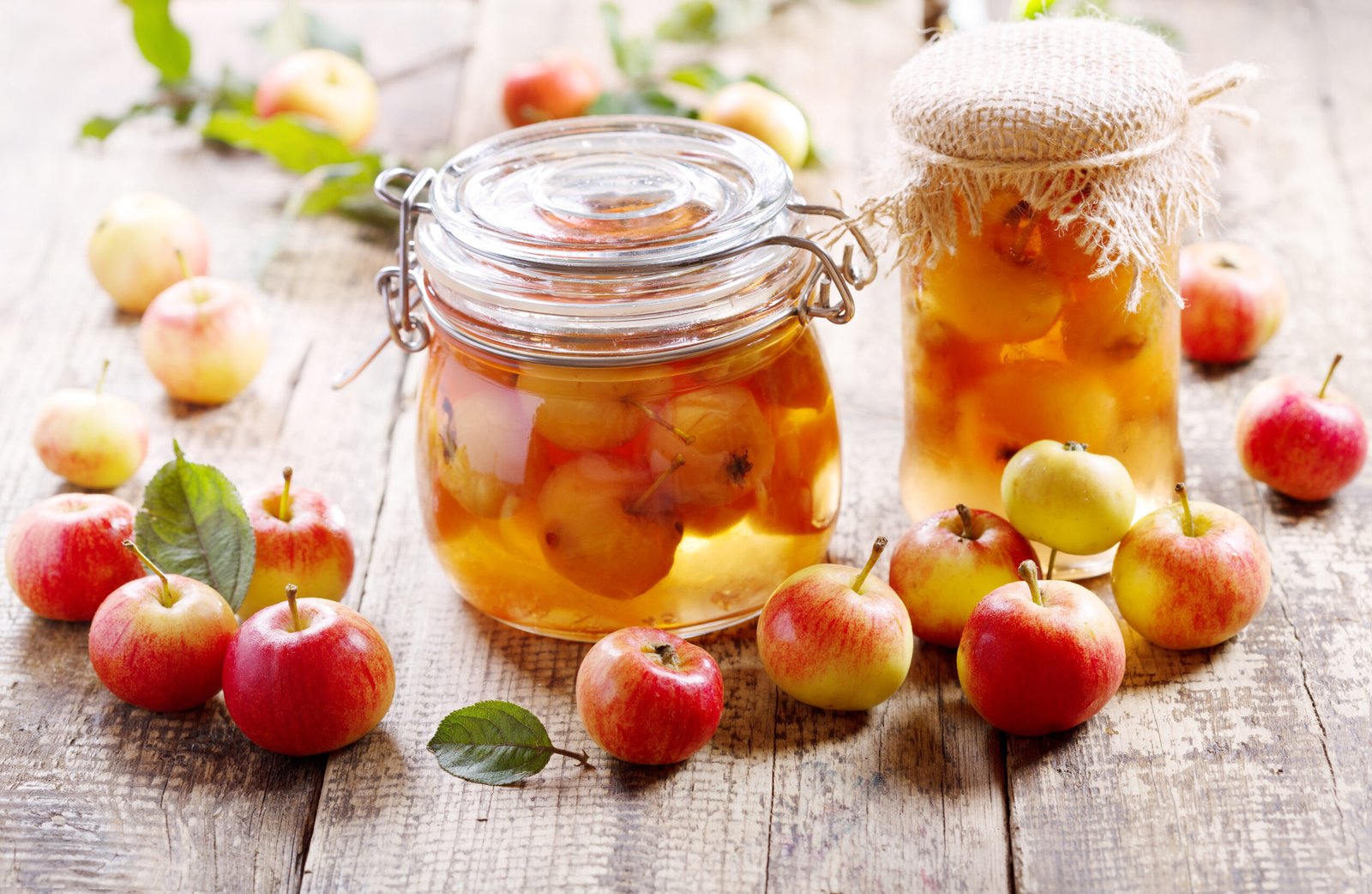 jars of apple jelly with small apples on a wood table