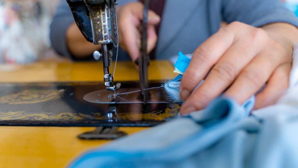 thread from a sewing machine being cut with blue fabric attached.